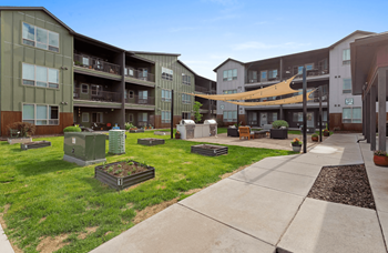 Apartment complex with green grass and trees.